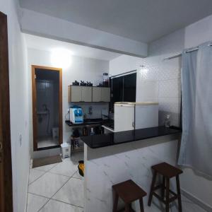 a kitchen with a counter and two stools in it at Kitnet São Diogo I in Serra