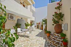 un patio con mesas, sillas y macetas en Margo Studios, en Naxos Chora