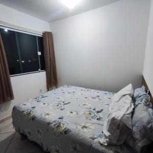 a bedroom with a bed with a blue comforter and a window at Kitnet São Diogo I in Serra +11 photos