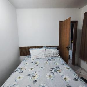 a bedroom with a bed with a floral bedspread at Kitnet São Diogo I in Serra