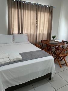 a bedroom with a large bed and a table at Flats Teles 3 in Palmas