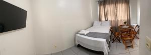 a small bedroom with a bed and a table at Flats Teles 3 in Palmas