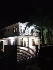 a white house with a fence in front of it at night at Hidalgo Home Apartment's in Moshi