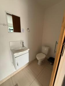 a bathroom with a toilet and a sink and a mirror at Suítes Ágape Festa do Peão in Barretos