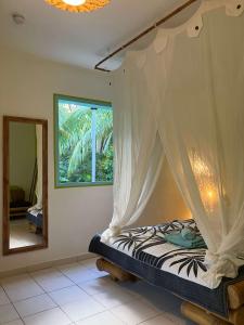 een slaapkamer met een hemelbed en een spiegel bij Gîte Zandoli Koko in Sainte-Anne