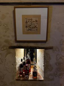 three bottles of alcohol sitting on a shelf under a picture at Le Relai Valdieu in Courgeon