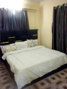 Un dormitorio con una cama grande con cabecero negro. en Richbee Hotel and Suites, en Abuja