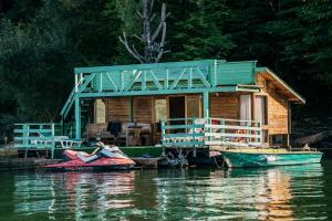 a house on the water with two boats in front of it at Casuta Verde Bicaz in Bicaz