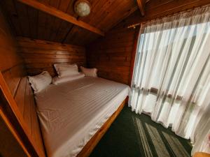 a small bed in a wooden room with a window at Casuta Verde Bicaz in Bicaz