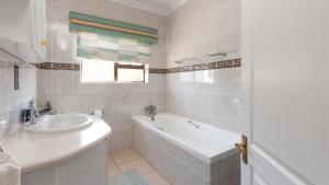 een witte badkamer met een bad en een wastafel bij Fly Me To The Moon Guesthouse in Mosselbaai +62 foto's