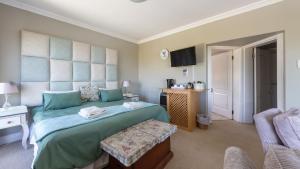 een slaapkamer met een groot bed en een stoel bij Fly Me To The Moon Guesthouse in Mosselbaai