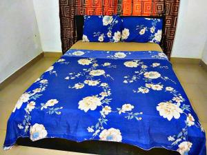 Un edredón azul con flores blancas en una cama en Richbee Hotel and Suites, en Abuja
