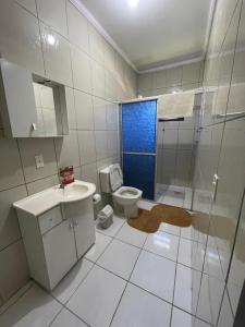 a bathroom with a toilet and a sink and a blue door at Hostel e Pousada Vó Lili in Joinville