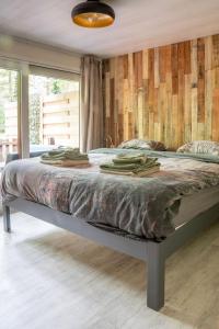 a bed in a bedroom with a wooden wall at Chalet Bos en Pootjes in Lanaken