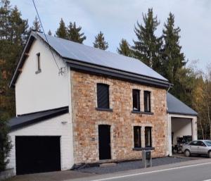 a brick and white house with a car on a street at Villa AIMÉ SALMCHÂTEAU in Vielsalm