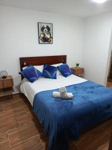 Apartamento Blue House Paipa في بايبا: غرفة نوم مع سرير ذو أغطية زرقاء ومخدات زرقاء