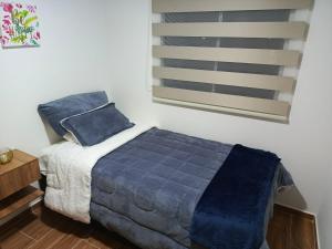 Apartamento Blue House Paipa في بايبا: غرفة نوم بسرير وملاءات زرقاء ونافذة +صورتان