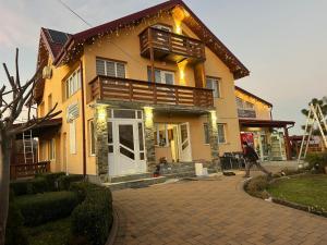 a woman walks past a house with a porch at Vila Onyx in Ţibăneşti