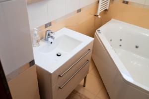 VulcanにあるChris Apartの洗面台と浴槽のある白いバスルーム +25枚の写真