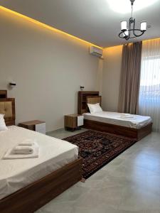 a bedroom with two beds and a rug at Shahristan Hotel in Aktau