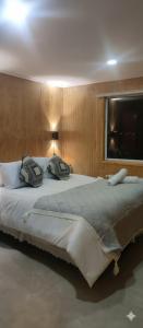 Una cama grande con dos almohadas encima. en Departamentos Dragones Puerto Natales, en Puerto Natales