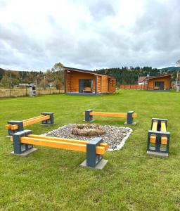 a group of benches in a field with a building at Casa Cub in Topliţa