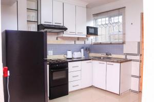 a kitchen with white cabinets and a black refrigerator at The Rest in Maseru