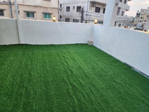 a balcony with green grass on top of a building at شقة مفروشة apartment amman alnuzzha in Amman