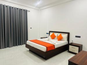 a bedroom with a bed with orange and white pillows at Shrek Villa in Balapitiya