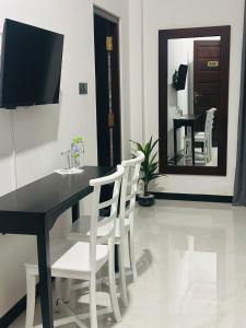 a black dining room table with white chairs and a mirror at Shrek Villa in Balapitiya
