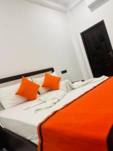 a bed with orange and white pillows on it at Shrek Villa in Balapitiya +2 photos
