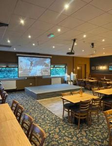 a restaurant with tables and chairs and a projection screen at Tree Top View Chalet in Caeathro +18 photos