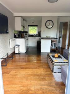 a kitchen and living room with a wooden floor at Tree Top View Chalet in Caeathro
