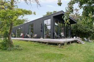 a black house with glass doors and a deck at Sea View, Sunrise And 200 Meters To The Water in Kalundborg