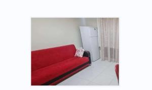 een rode bank in een woonkamer met een koelkast bij Özlem Apart&Pansiyon in Hatay