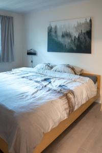 a large bed in a bedroom with a painting on the wall at Sakurahuisje in Lanaken