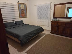 a bedroom with a bed and a dresser and a window at הבית במושב in Umm el Shuf