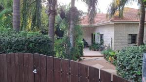 a fence in front of a house with palm trees at הבית במושב in Umm el Shuf