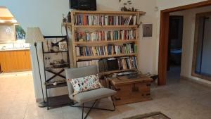 a room with a chair and a book shelf with books at הבית במושב in Umm el Shuf
