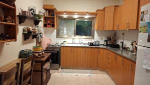 a kitchen with wooden cabinets and a sink and a window at הבית במושב in Umm el Shuf +5 photos