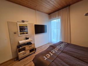 a bedroom with a bed and a flat screen tv at Ferienhaus DaPfusterer in Bad Mitterndorf