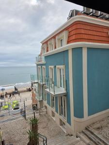 a building on a beach next to the ocean at 2SEA - Apartamento na praia do Ouro - Sesimbra in Sesimbra