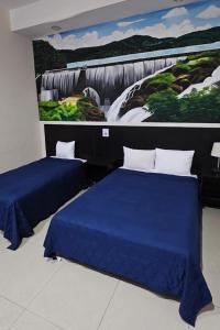two beds in a room with a painting on the wall at Hotel Mágico del Mar in La Paz