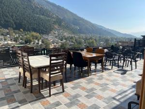 a restaurant with tables and chairs on a balcony at Nawab's Hotel Balakot in Bālākot +7 photos