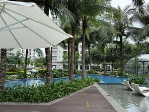 a swimming pool with a white umbrella and palm trees at Elite Apartment - Resort Pool & Gym by Center HCMC in Ho Chi Minh City