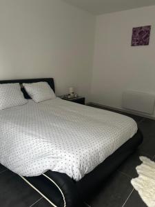 a bed in a bedroom with a white wall at Appartement cosy in Montier-en-Der