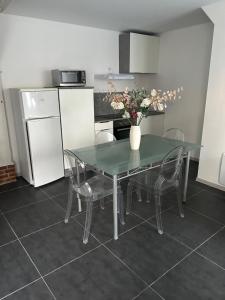 a kitchen with a glass table and chairs and a refrigerator at Appartement cosy in Montier-en-Der
