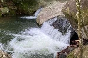 a river with rapids on the side of a rock at Pousada Magia da Aldeia in Silva Jardim