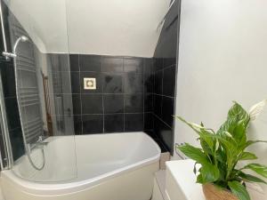 a bathroom with a white tub and a black tiled wall at Perfectly located and cozy flat in Bury Saint Edmunds