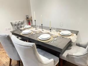 a dining room table with white plates and chairs at Perfectly located and cozy flat in Bury Saint Edmunds